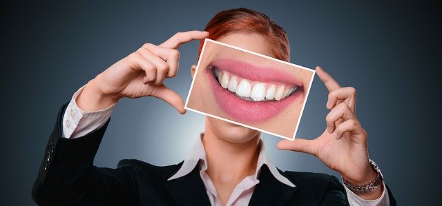 綺麗な歯並びの口元の写真を持つ女性