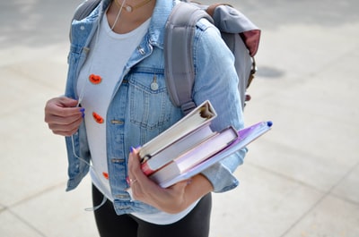 教科書とノートを抱える大学生