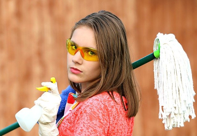 ゴーグルをして掃除用具を持つ女性