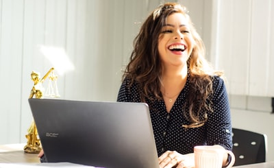 パソコンから顔を上げて笑いかける女性