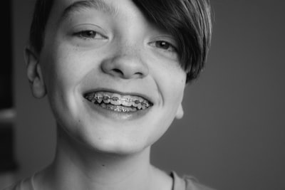 矯正器具をつけた歯を見せながら笑う少年