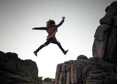 大きな岩の間を飛び越える女性