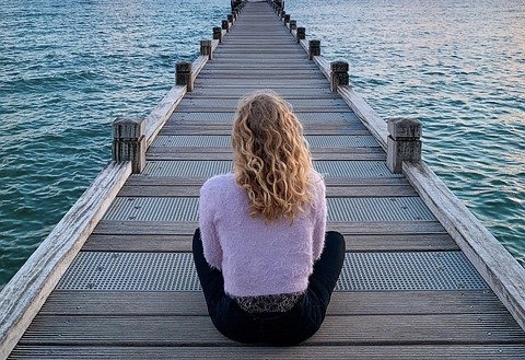 桟橋に座り、海を眺める女性